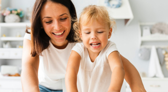 Una mujer adulta y un niño pequeño sonriendo en un entorno hogareño luminoso.