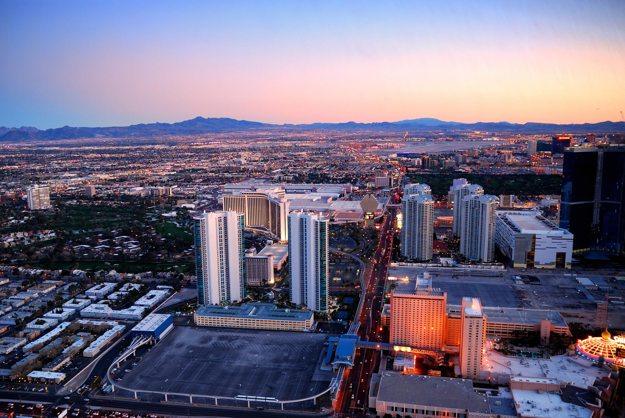 Toma aérea del centro de Las Vegas al atardecer, con montañas al fondo y ciudad al frente