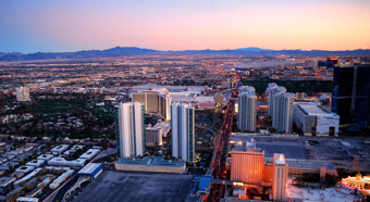 Toma aérea del centro de Las Vegas al atardecer, con montañas al fondo y ciudad al frente