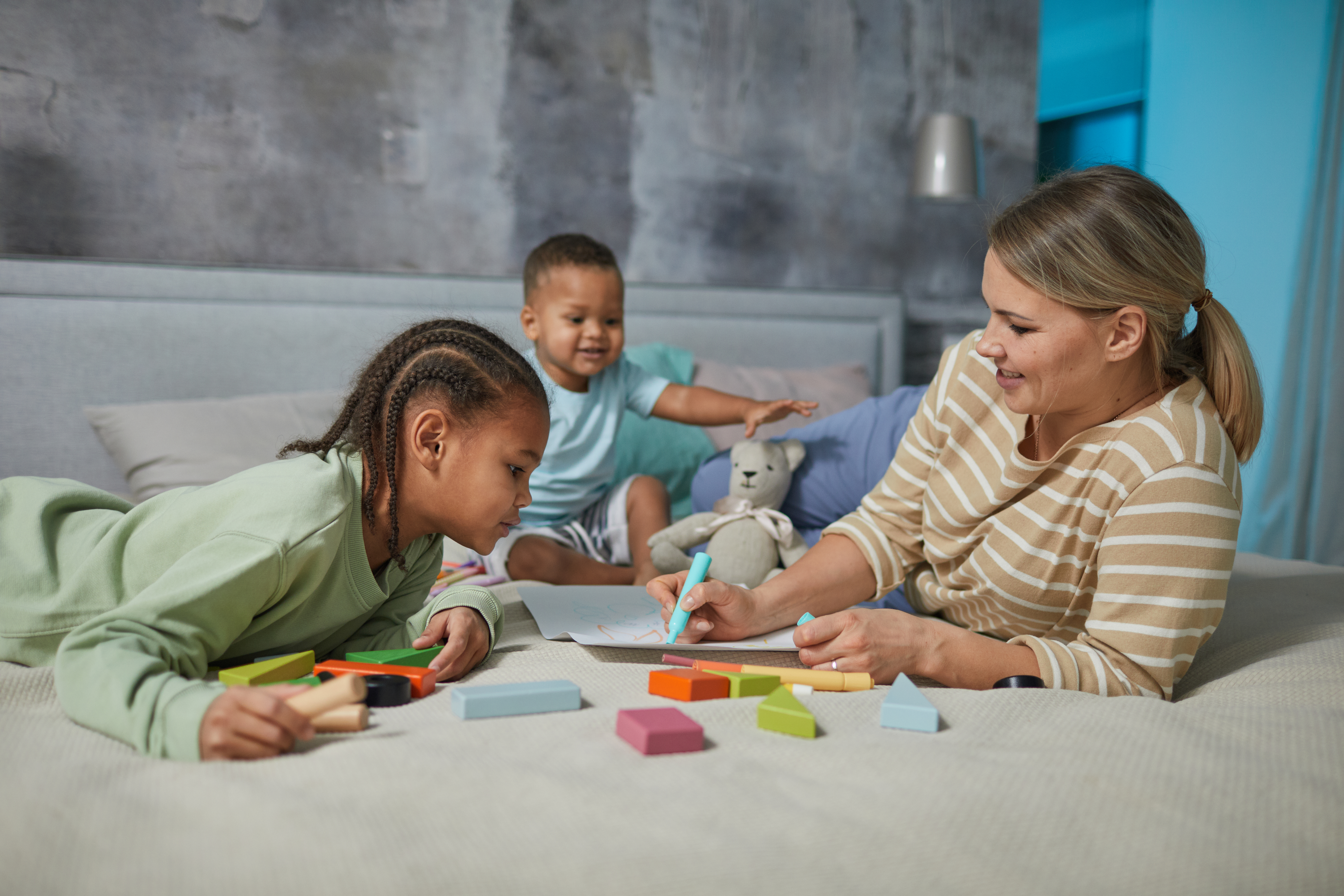 Mujeres con dos niños pequeños en una guardería en casa jugando con juguetes