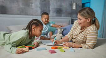 Mujeres con dos niños pequeños en una guardería en casa jugando con juguetes