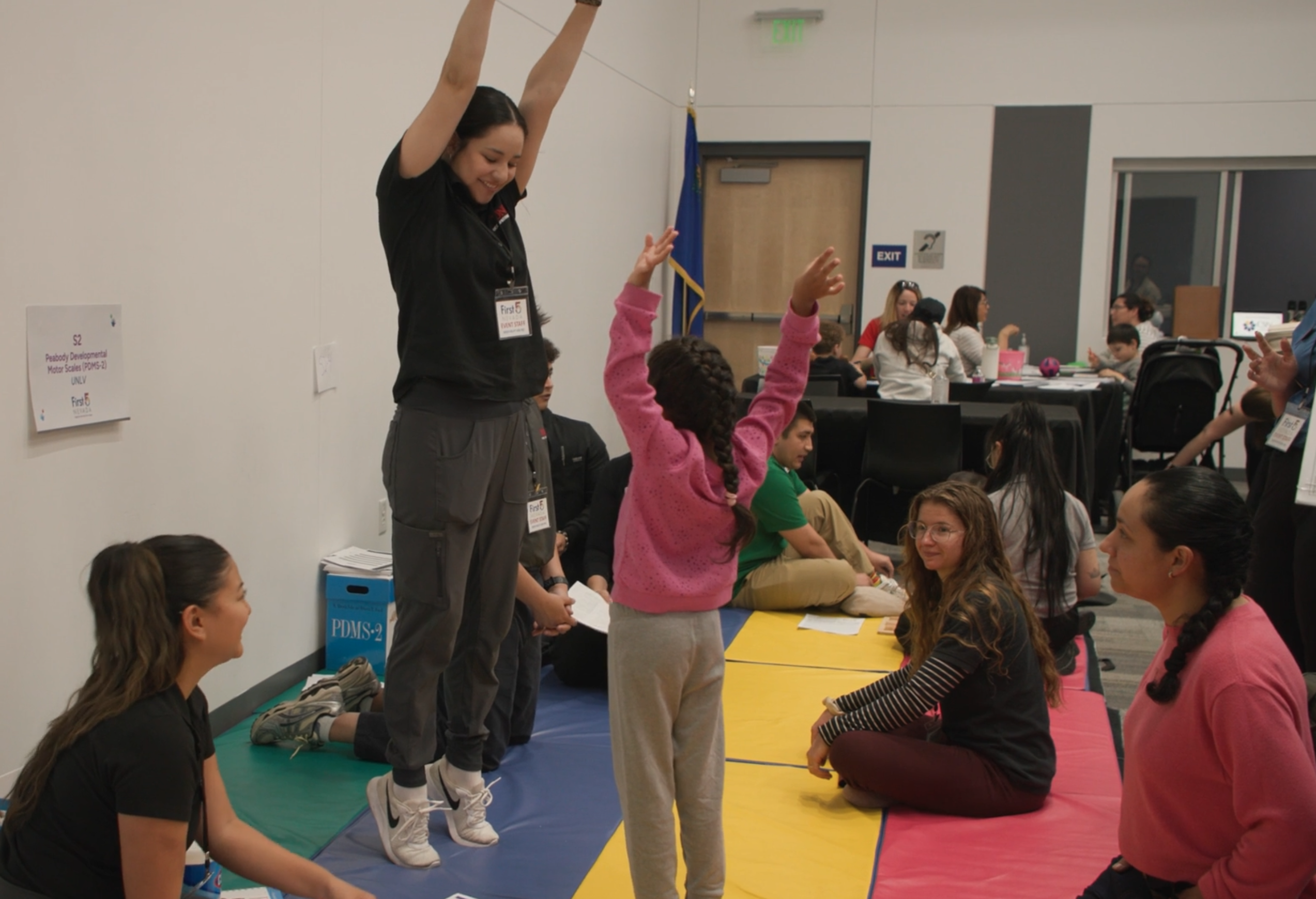 Mujeres saltando en el aire durante un evento de proyección, una niña hace lo mismo