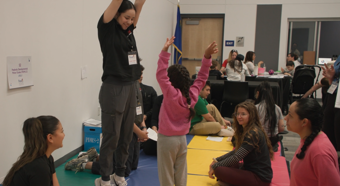 Mujeres saltando en el aire durante un evento de proyección, una niña hace lo mismo