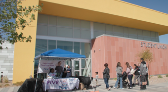 Vista exterior de un edificio de la Unión de Estudiantes con un stand de First 5 Nevada instalado afuera. Personas entrando al evento.