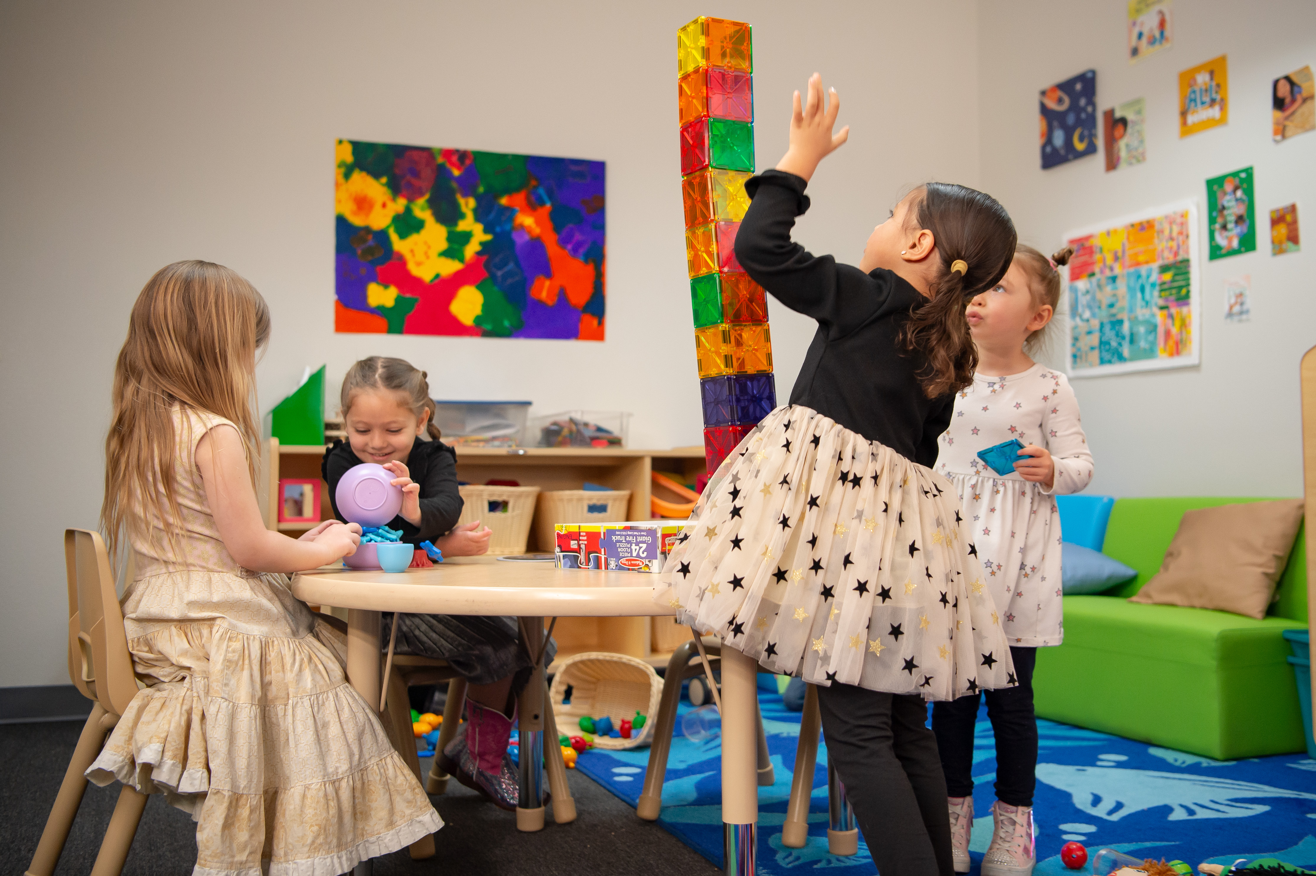 Cuatro niñas en un aula colorida jugando con juguetes