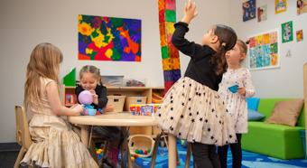 Cuatro niñas en un aula colorida jugando con juguetes