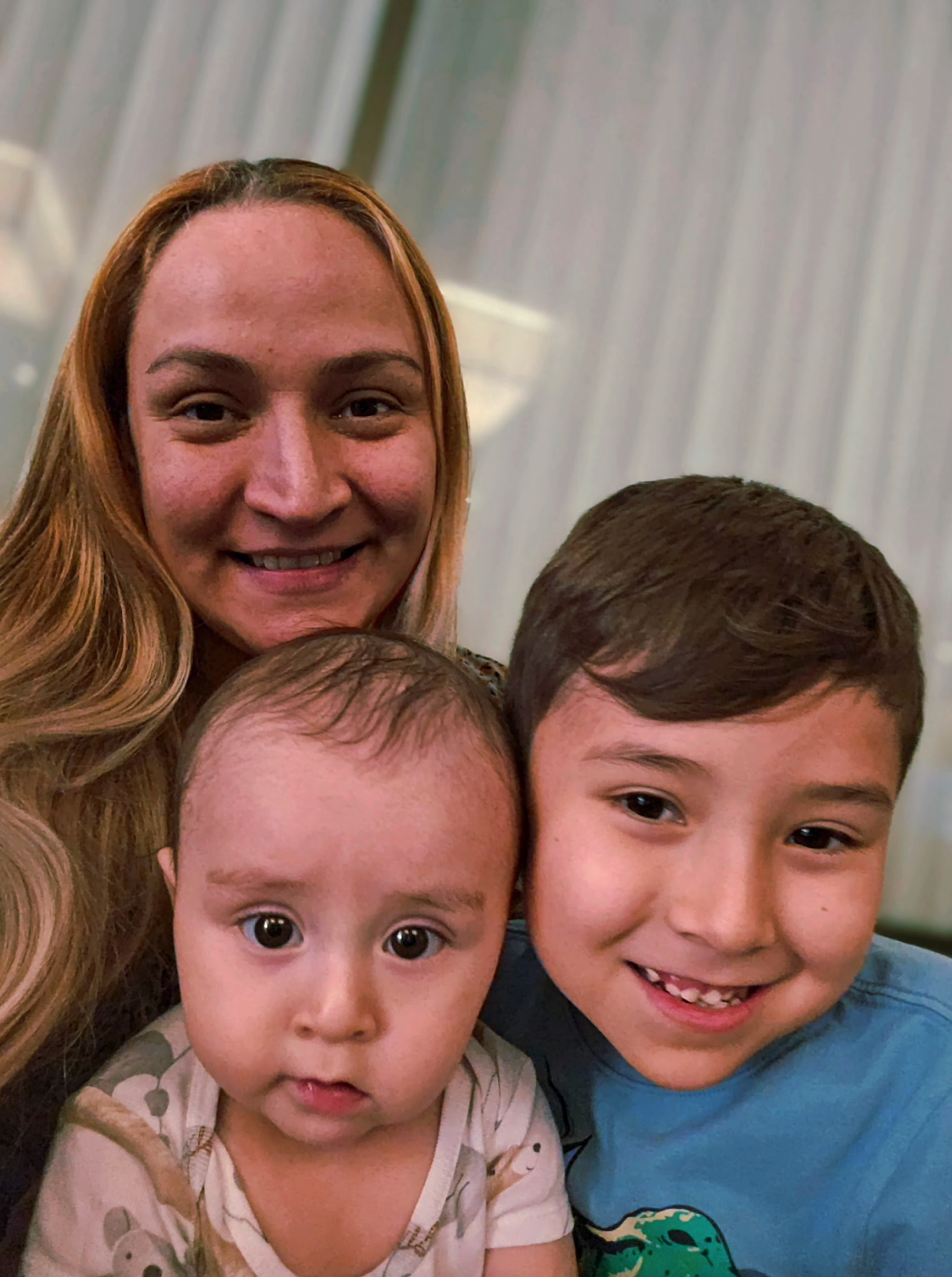 Una mujer adulta y dos niños pequeños sonríen a la cámara mientras publican una foto