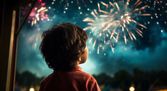 Un joven con el pelo castaño y desgreñado y un polo rojo mira fijamente el cielo nocturno mientras se disparan fuegos artificiales de varios colores.