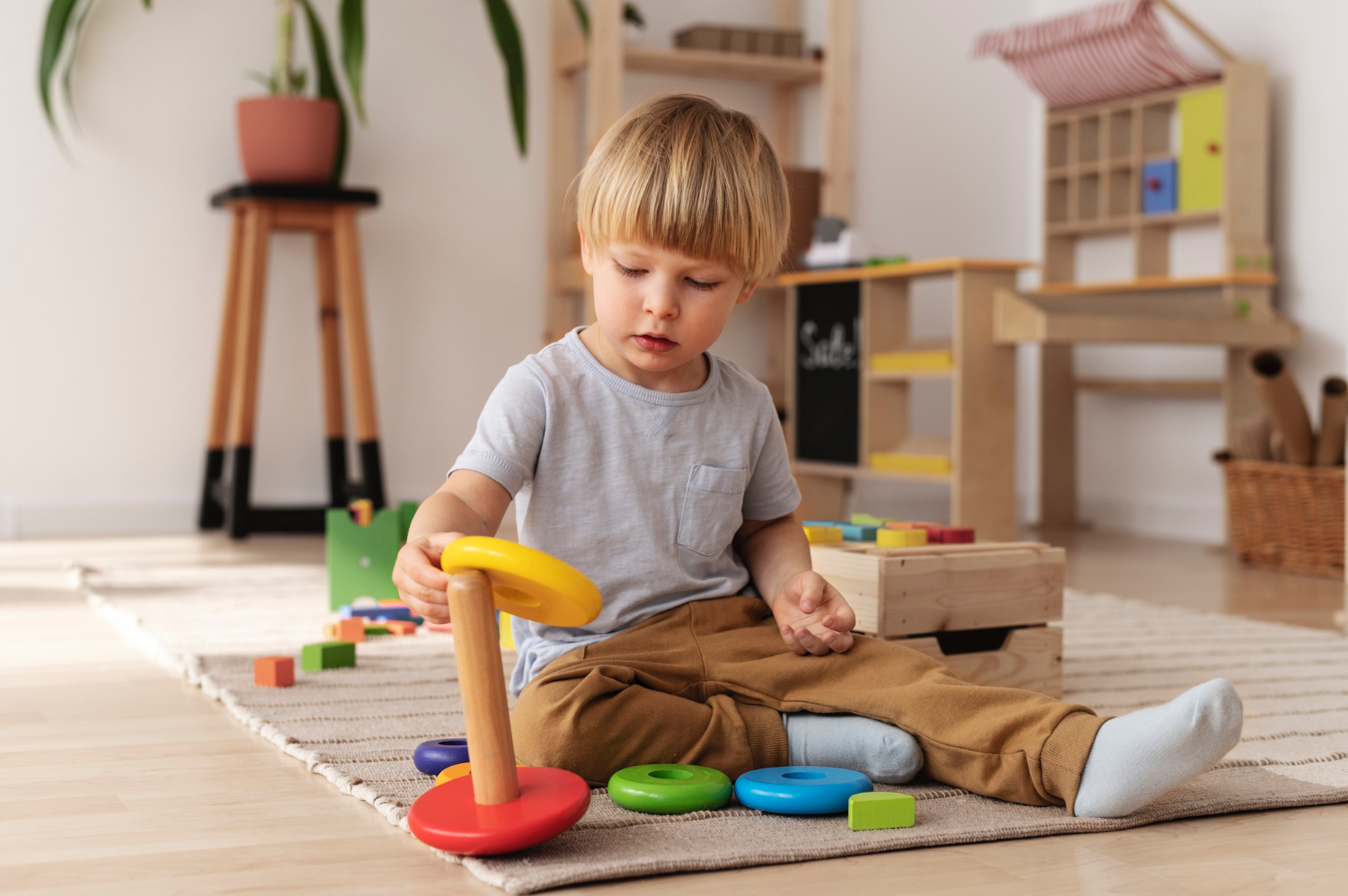 Un niño pequeño se sienta en el suelo y juega con juguetes de bloques de colores.