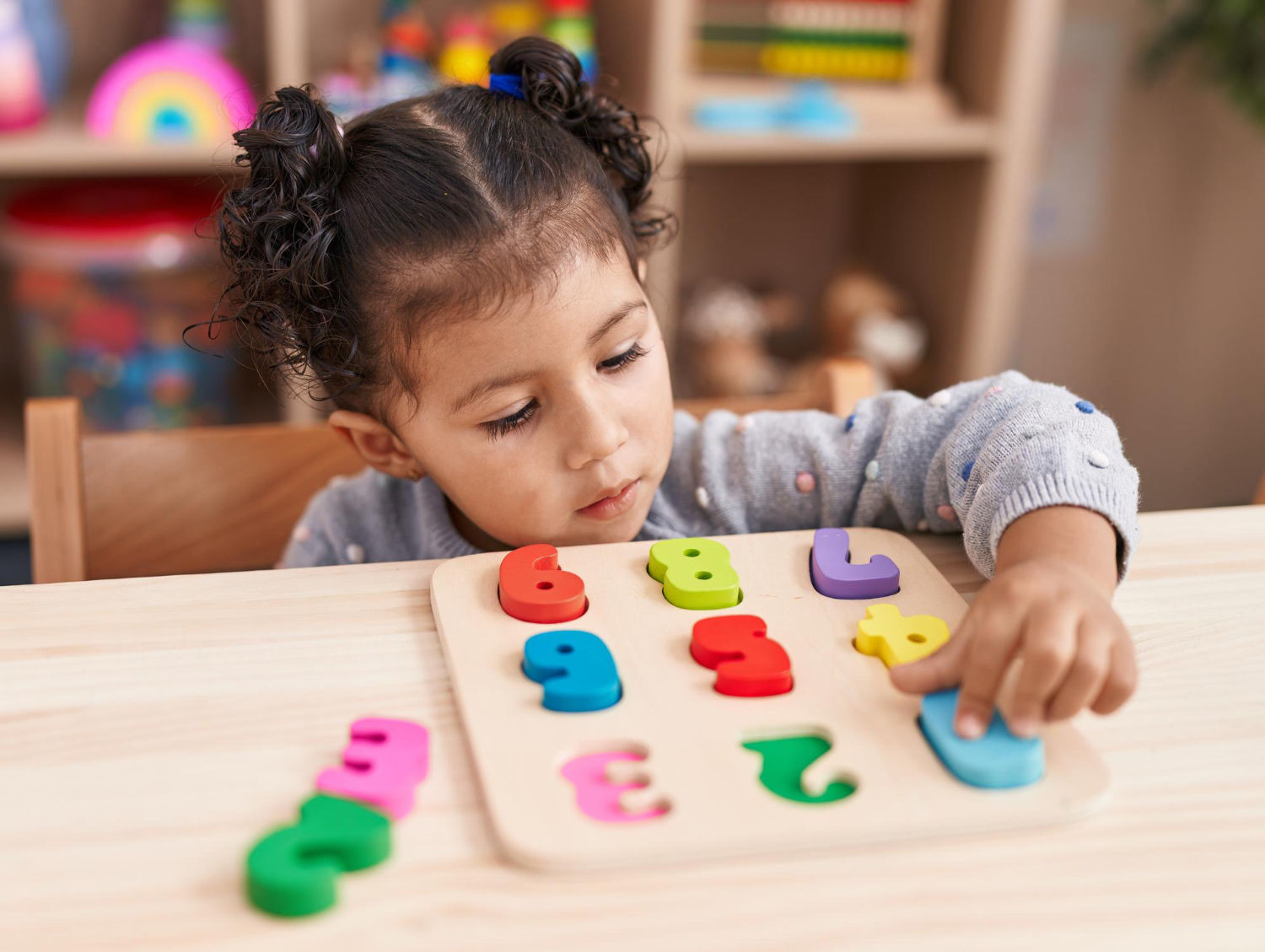 Una niña en un aula colorida juega con un juguete de números coloridos