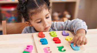 Una niña en un aula colorida juega con un juguete de números coloridos
