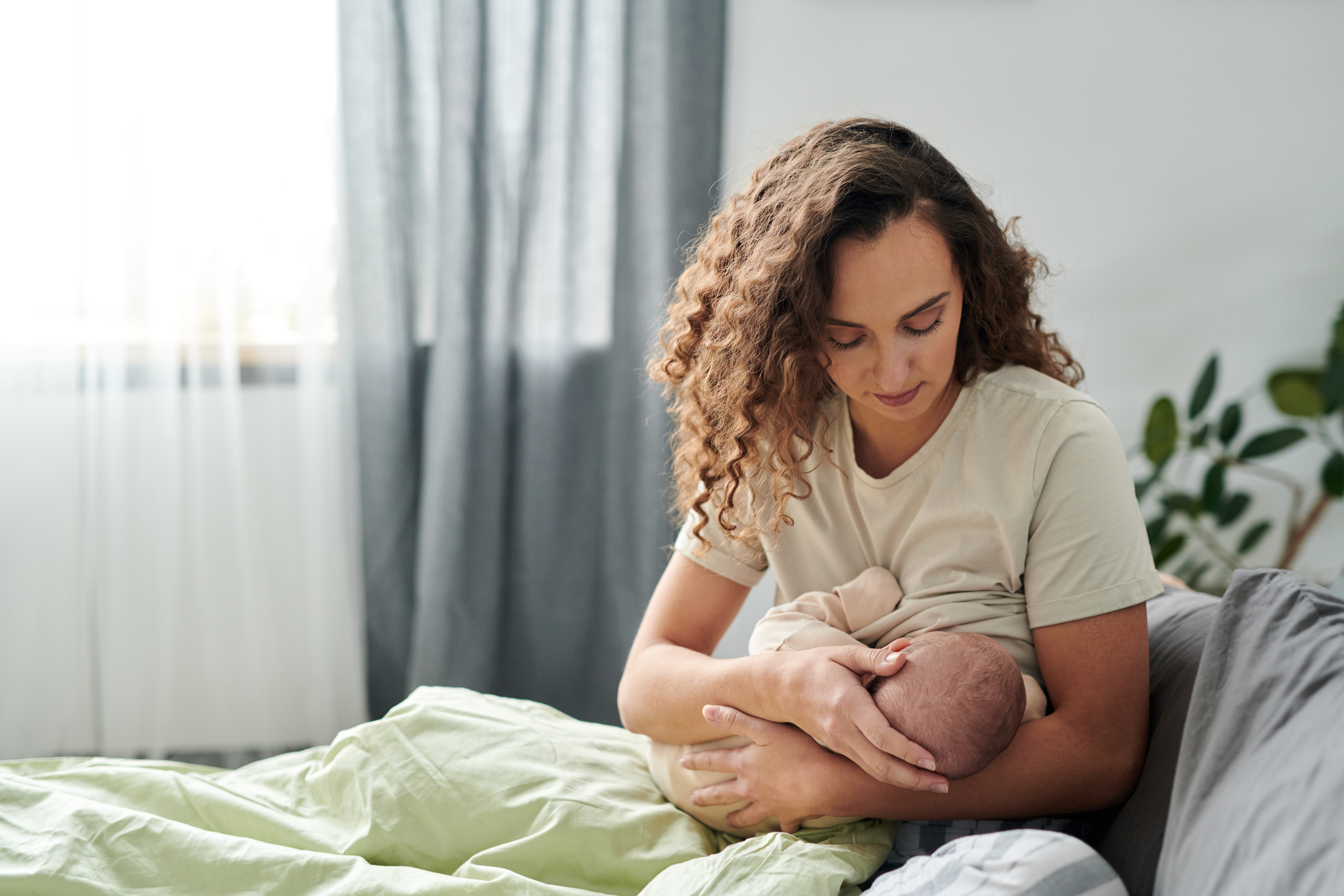 Mujeres en una habitación acogedora sentadas en la cama mientras amamantan.
