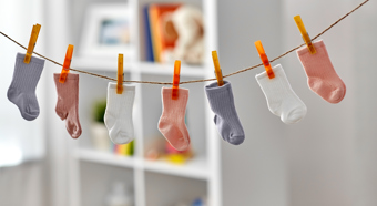 7 calcetines de colores para niños pequeños colgados en un tendedero en el interior.