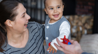 Mujer adulta sosteniendo a un niño pequeño sonriente.