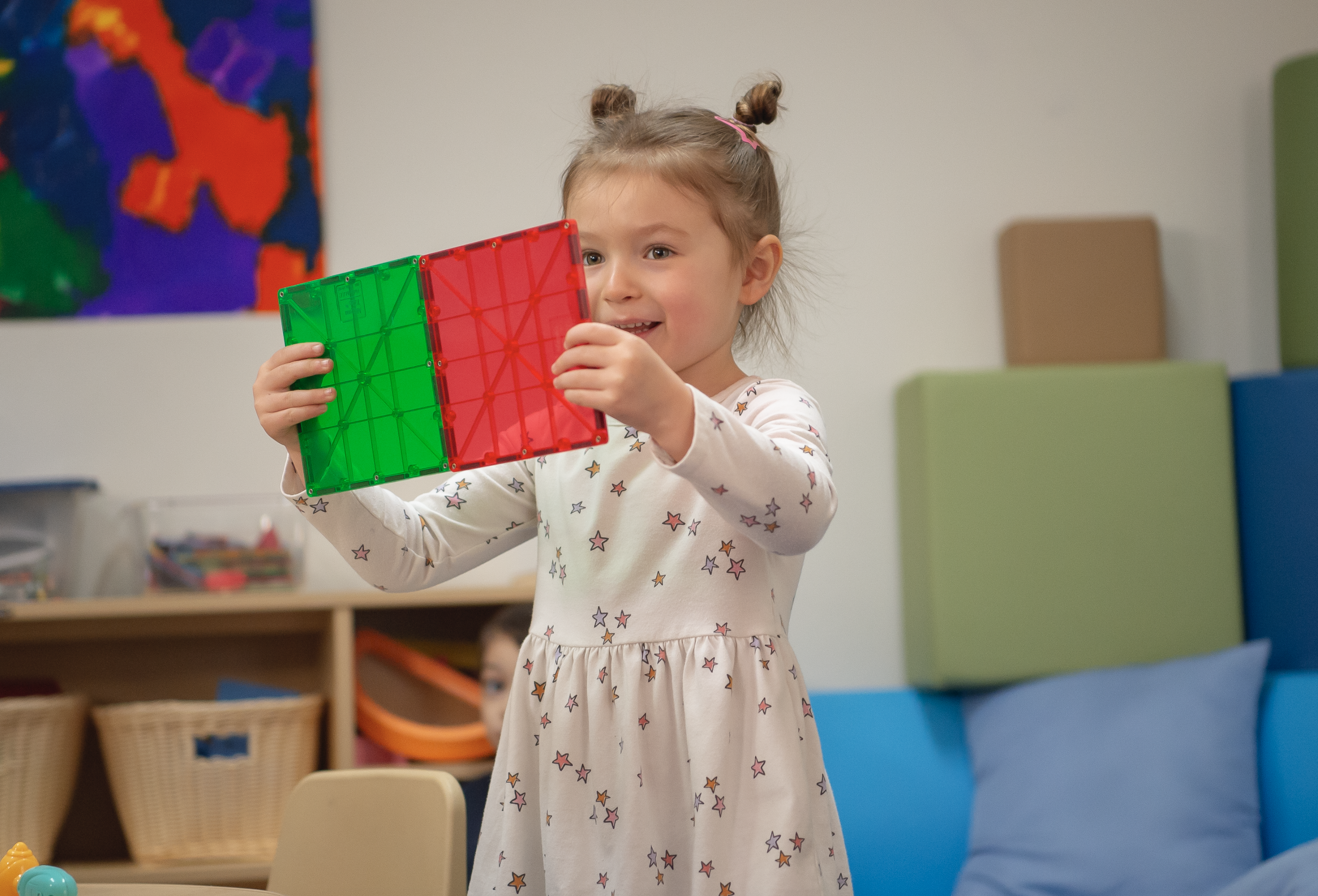 Niña jugando con juguetes rojos y verdes en un salón de clases