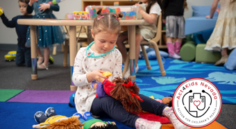 Niña jugando con muñecas en un entorno escolar con otros niños