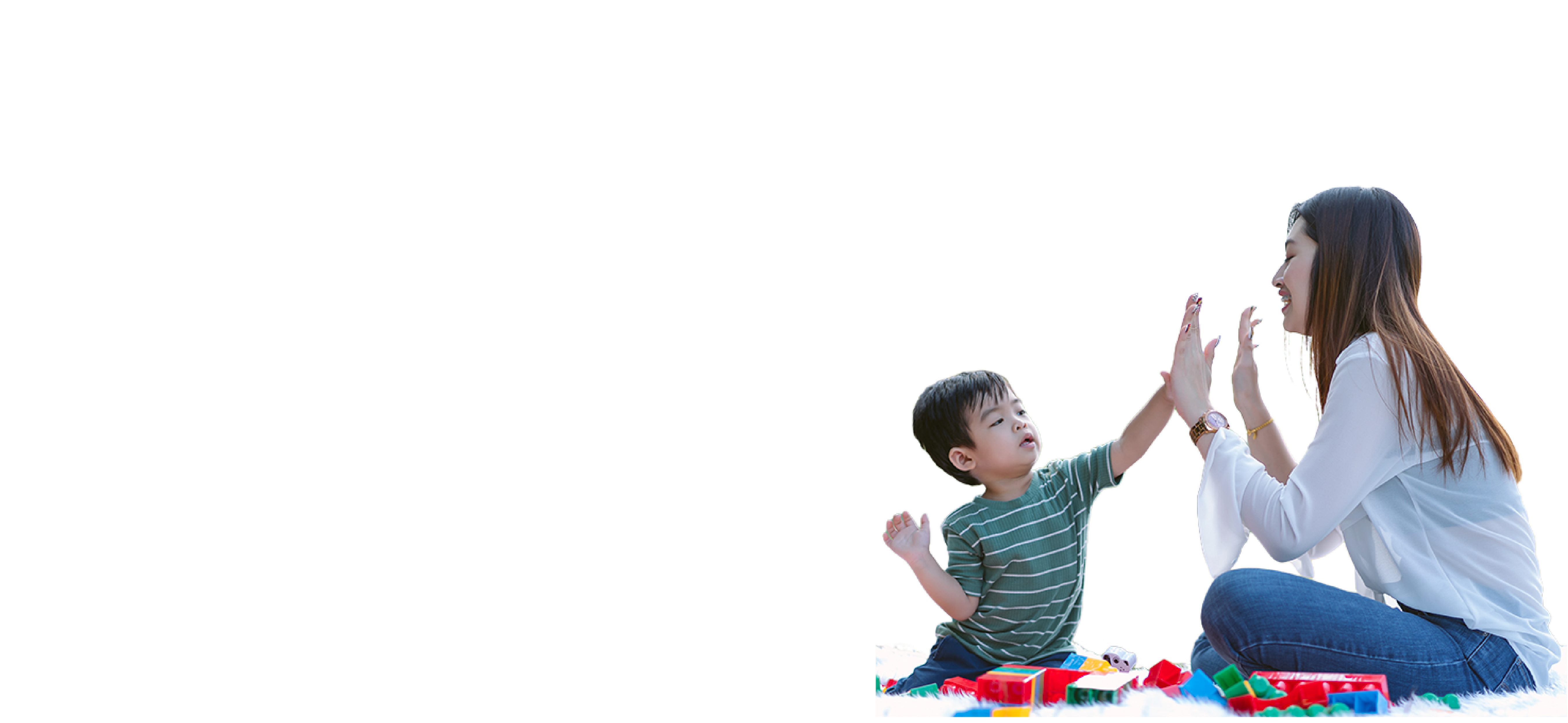 Niño de tez clara y pelo oscuro, vistiendo una remera verde con rayas claras, chocándole los cinco a una mujer de tez clara y pelo marrón, vestida con una camisa blanca y pantalón de denim, y bloques de colores de juguete alrededor.