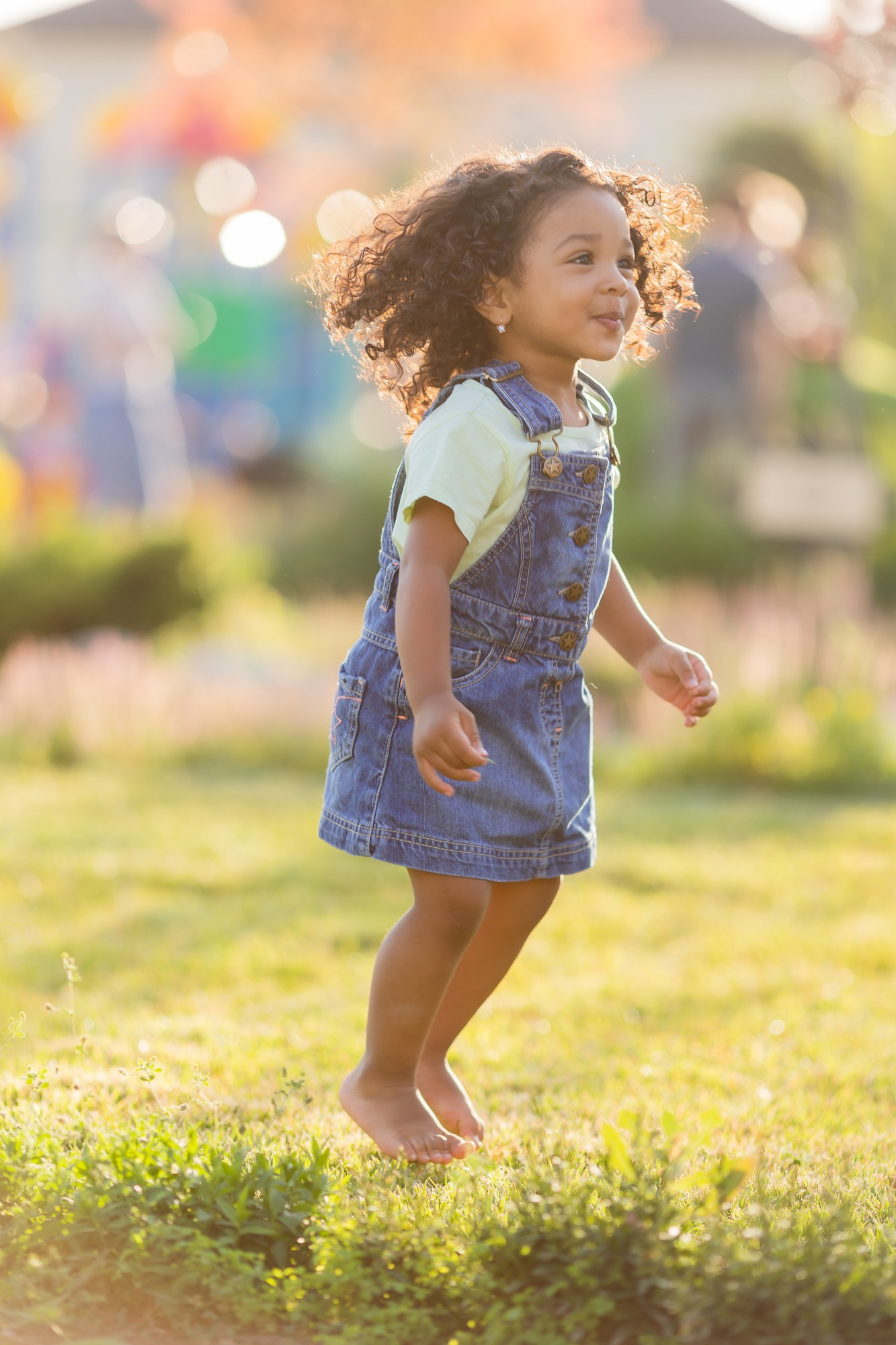 Un niño pequeño sonriente en un entorno exterior luminoso, jugando en la hierba.