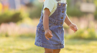 Un niño pequeño sonriente en un entorno exterior luminoso, jugando en la hierba.