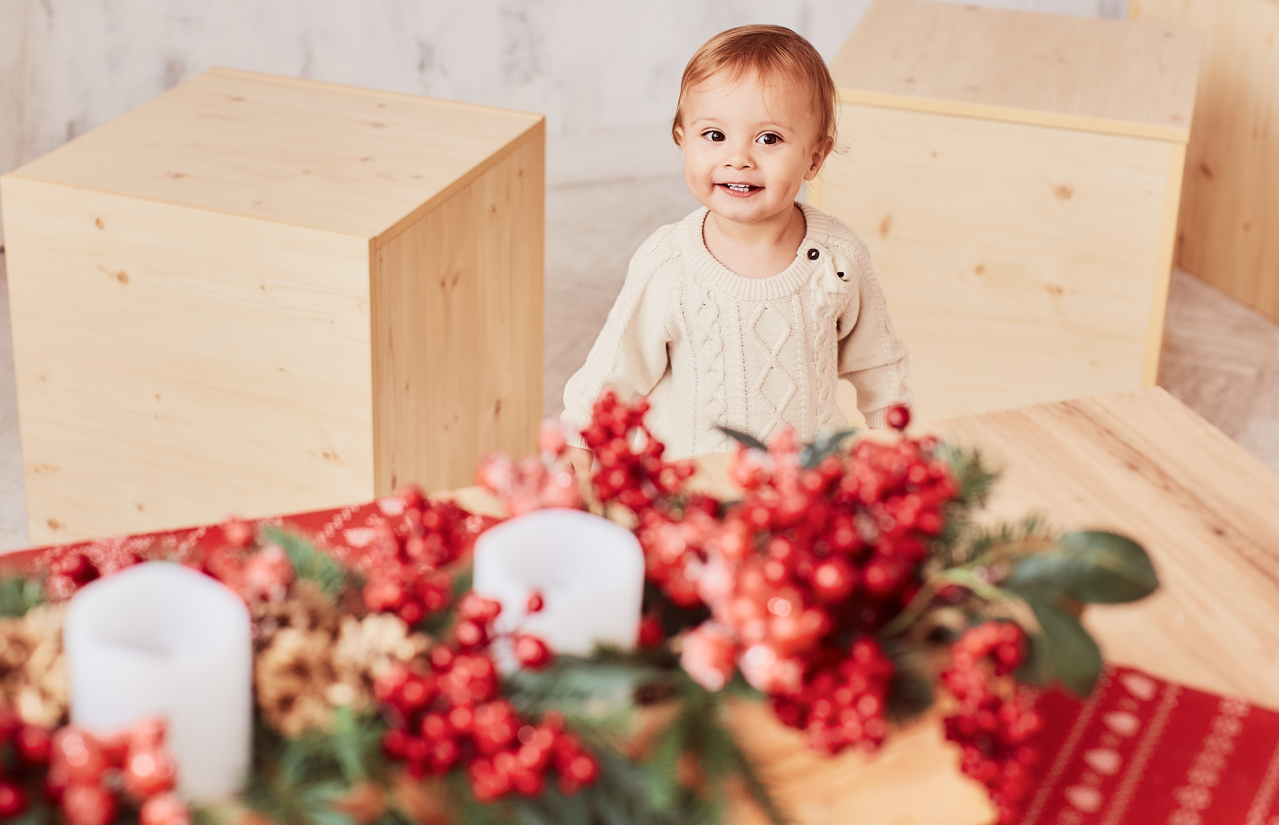 Una linda niña sonríe mientras está parada en una habitación con decoraciones navideñas a su alrededor