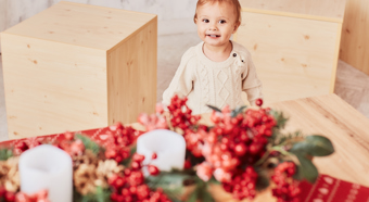 Una linda niña sonríe mientras está parada en una habitación con decoraciones navideñas a su alrededor