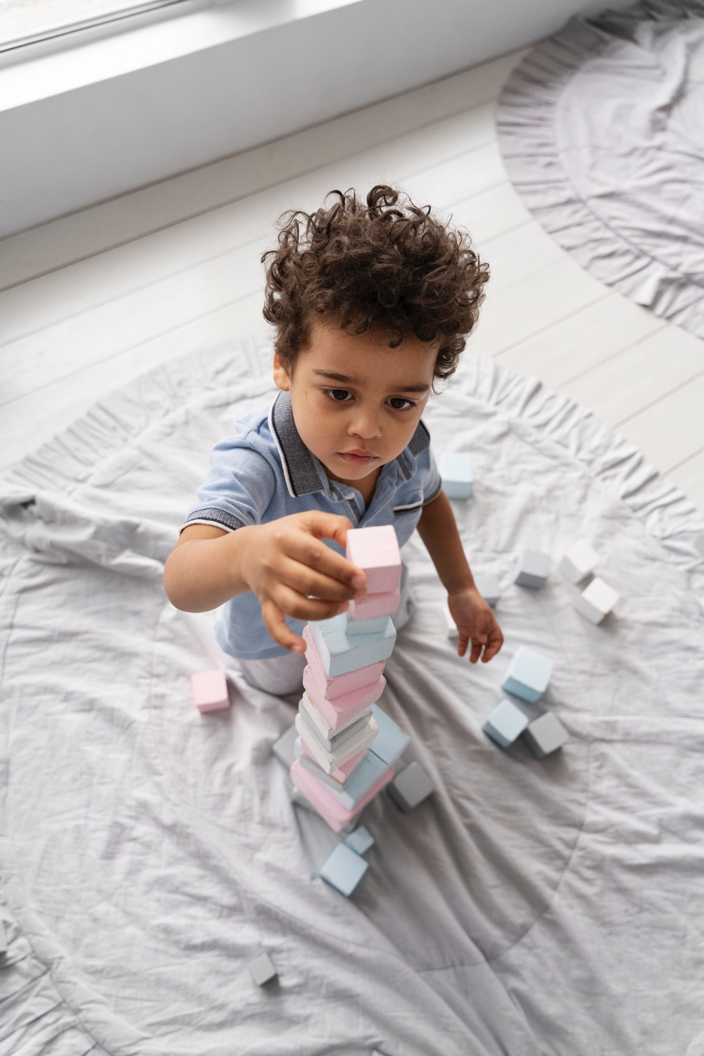 Primer plano de un niño pequeño apilando pequeños bloques en un cómodo entorno hogareño.